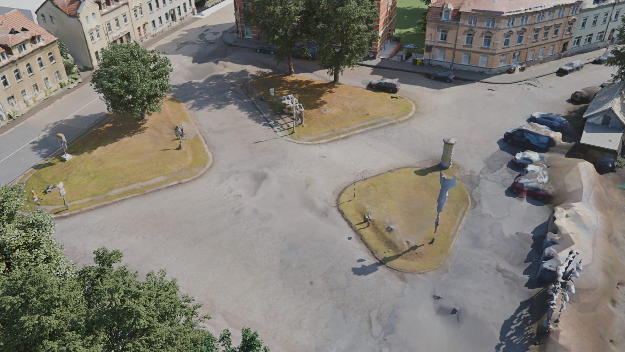 Der Löbauer Platz heute aus der Vogelperspektive: eine große, graue Asphalt- und Pflasterfläche mit drei Rasen-Verkehrsinseln, darauf einzelne Bäume, Schilder und eine Litfaßsäule. Am rechten Rand parken Autos, ringsum stehen mehrgeschossige Altbauten.